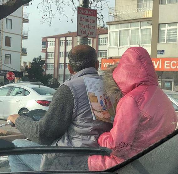 Sürücülerin dikkatini çekti... Motosiklet üzerinde ders kitabını okudu