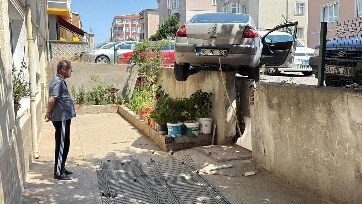 El freni çekilmeyen otomobil, hareket edip istinat duvarında asılı kaldı haber görseli
