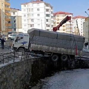 Buzda kayan kamyon, derenin duvarında asılı kaldı