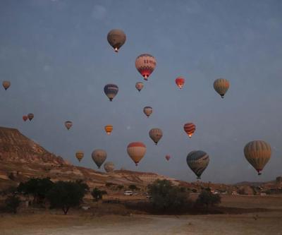 Kapadokya’ya tatil için gelen turistler, bölgeyi sıcak hava balonuyla izliyor