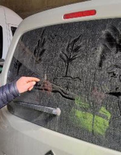 Temizlik görevlisi, tozlu araç camlarını tabloya dönüştürüyor