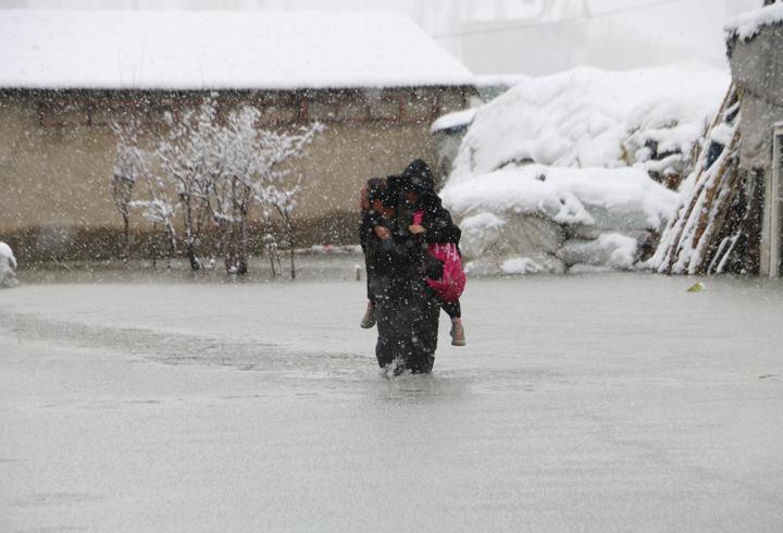 Evinin önünde biriken su nedeniyle çocuklarını sırtında taşıyor