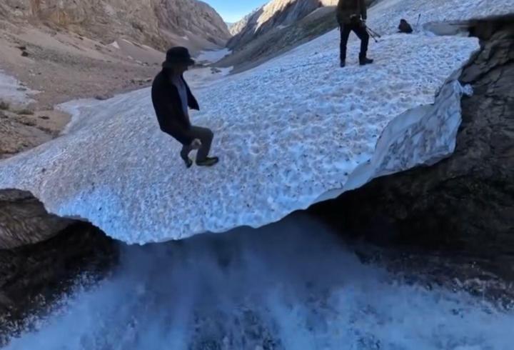 Altında su geçen kar kütlesinin üzerindeki tehlikeli yürüyüş kamerada