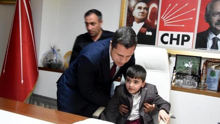 Koltuğa ulaşamayan küçük başkanı kucaklayarak yerine oturttu