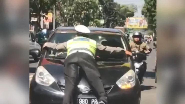 Trafik polisi, kırmızı ışıkta geçen otomobilin kaputuna çıktı