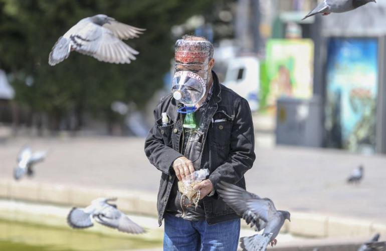Pet şişeden maskesiyle kuşların karnını doyurdu